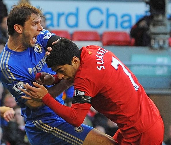 Liverpool's Uruguayan striker Luis Suarez (R) clashes with Chelsea's Serbian defender Branislav Ivanovic (L) after appearing to bite the Chelsea player during the English Premier League football match between Liverpool and Chelsea at the Anfield stadium in Liverpool, northwest England, on April 21, 2013. Liverpool striker Luis Suarez on April 21 apologised for biting Chelsea defender Branislav Ivanovic during the sides' 2-2 Premier League draw at Anfield. The incident occurred mid-way through the second half, with Liverpool trailing 2-1 following a tussle in the penalty area. AFP PHOTO / ANDREW YATES RESTRICTED TO EDITORIAL USE. No use with unauthorized audio, video, data, fixture lists, club/league logos or ?live? services. Online in-match use limited to 45 images, no video emulation. No use in betting, games or single club/league/player publications. (Photo credit should read ANDREW YATES/AFP/Getty Images)